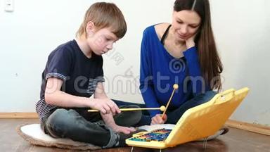 演奏音乐乐器。 老师教男孩玩木琴